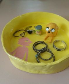 a yellow bowl filled with lots of assorted rings and other items on top of a table