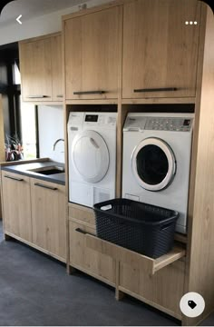 a washer and dryer in a room with wooden cabinets on either side of the washer and dryer