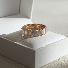 a gold ring with three baguets in it sitting on top of a white box