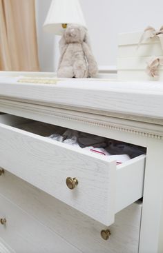 a teddy bear sitting on top of a white dresser