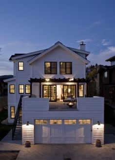 a large white house with lots of windows and lights on it's front porch