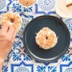 a person is eating a donut on a blue and white tablecloth with plates