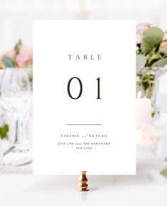 a table number card sitting on top of a table next to some flowers and candles