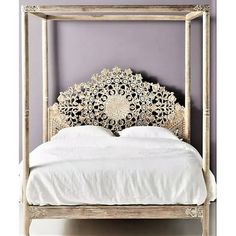 a white bed with an intricate headboard and foot board in front of a purple wall