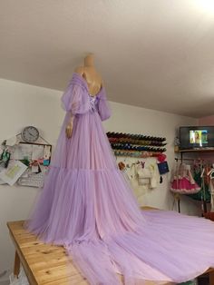 a mannequin is dressed up in a long purple dress on a wooden table