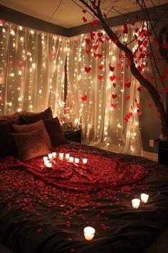 a bed topped with lots of candles next to a wall covered in lights and hearts