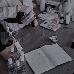 an open book sitting on top of a wooden table next to bottles and other items