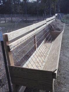 a wooden bench sitting in the middle of a field next to a wire and wood fence