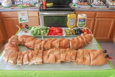 a table topped with sandwiches and vegetables on top of a green counter covered in condiments