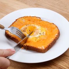 someone is cutting into a piece of bread with an egg in it on a white plate