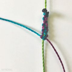 a close up of a piece of yarn on a white surface with one knot in the middle