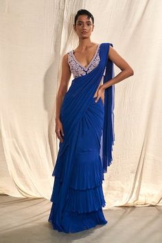 Blue pre-draped saree with multi layered tiered border, pleated draped details and attached pallu. Paired with V neck blouse with all over floral pattern, contrast cut dana and sequin embroidery. - Aza Fashions Elegant Blue Pre-draped Saree, Blue Georgette Draped Saree, Blue Draped Saree With Cutdana, Fitted Blue Draped Saree, Fitted Draped Blue Blouse Piece, Blue Draped Festive Dresses, Festive Draped Blue Dresses, Festive Blue Draped Dress, Blue Pre-draped Festive Dress