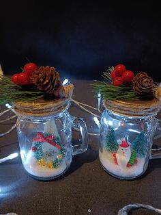 two glass mugs decorated with snowmen and pine cones