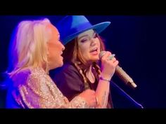 two women with hats on singing into microphones