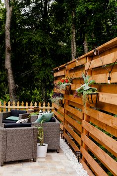 a wooden fence next to a patio with two chairs and a couch on it's side