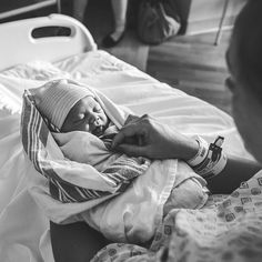 a woman holding a baby in her arms while laying on a bed with other people nearby