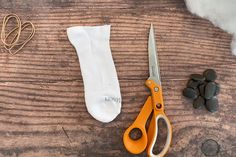 the scissors are next to some rocks and cotton on the table with it's contents