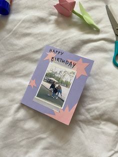 a happy birthday card on top of a bed next to scissors