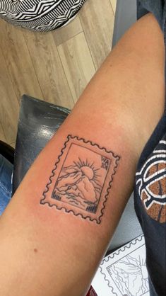 a woman's arm with a stamp on it that has an image of a mountain