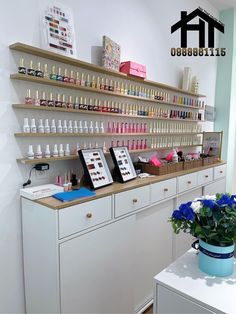 the inside of a nail salon with flowers and bottles on the counter, along with shelves full of manicures