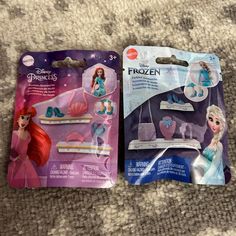 two frozen princess toys are laying on the floor next to each other in their packaging