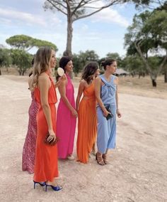 four women in dresses are standing together and talking to each other while one woman is holding an ice cream cone