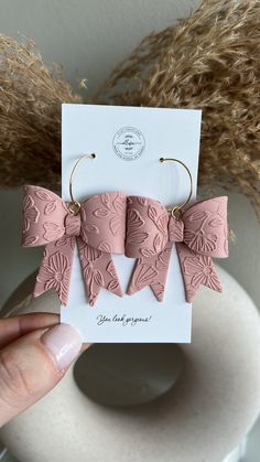 a pair of pink bows are held up in front of a white card with the word love on it