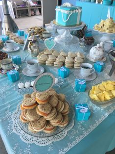 a table topped with lots of desserts and pastries on top of a blue table cloth