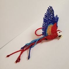 the beaded bird is red, white and blue with feathers on it's tail