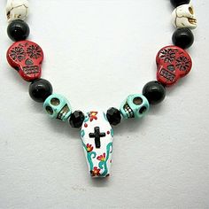 Elevate Your Festive Attire With This Choker-Length Necklace, A Vibrant Celebration Of Life And Remembrance. Central To Its Design Is A White Wooden Bead, Meticulously Hand-Painted To Resemble A Coffin. This Unique Piece Is Artfully Flanked By Turquoise-Dyed Howlite Skull Beads, Adding A Touch Of Dia De Los Muertos Tradition. Glass Black Beads In Varying Sizes Provide A Dramatic Contrast, Creating A Stunning Visual. Perfect For Cinco De Mayo, Dia De Los Muertos, And Festival Season Outfits, This Gothic White Jewelry For Festivals, White Gothic Jewelry For Festivals, White Gothic Skull Jewelry, White Bohemian Skull Jewelry, White Gothic Festival Jewelry, Gothic White Festival Jewelry, White Skull Jewelry For Day Of The Dead, White Skull Print Jewelry For Gift, White Skull Print Jewelry Gift