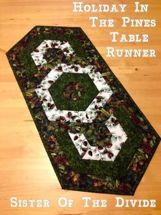 the table runner is made up of pine cones and holly leaves, along with holiday in the pines