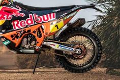 a red bull dirt bike parked on top of a dirt field