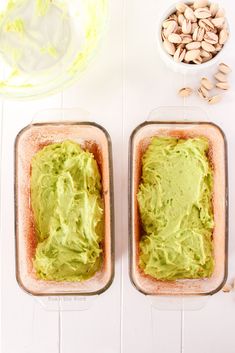 two pans filled with guacamole sitting on top of a white table