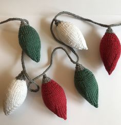 knitted christmas lights hanging from string on white surface with red, green and white decorations