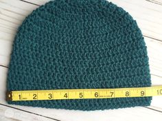 a green crocheted hat with a measuring tape