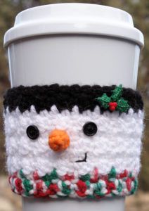 a close up of a coffee cup cozying with a snowman face on it