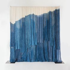 an abstract painting with blue and white colors on the wall next to a black metal stand