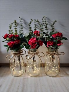 three mason jars with red roses in them