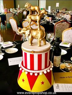 a circus themed cake on top of a table with wine glasses and plates around it