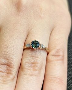 a woman's hand with a ring on it that has three stones in the middle