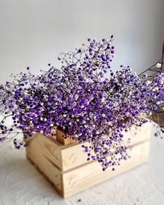 purple flowers in a wooden crate on a table