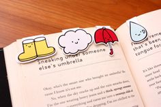 an open book with stickers on the pages and pictures of umbrellas, boots, and raindrops