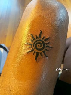 a tattoo on the leg of a person with sun and spirals in black ink