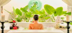 a woman sitting in a bathtub surrounded by greenery