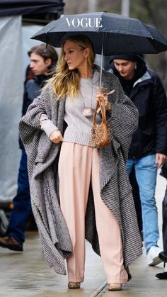 a woman is walking down the street with an umbrella in her hand and another person behind her