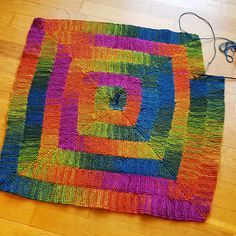 a multicolored rug is laying on the floor next to a pair of scissors