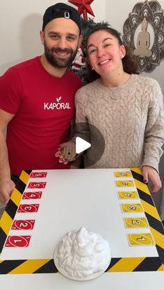 a man and woman standing in front of a table with a cake on top of it