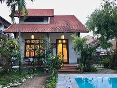 a house with a pool in front of it and some trees around the back yard