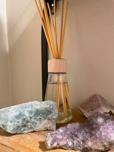 some rocks and sticks on a table next to a glass bottle with reeds in it