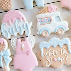 baby shower cookies are arranged on a wooden table with pink and blue onesuits